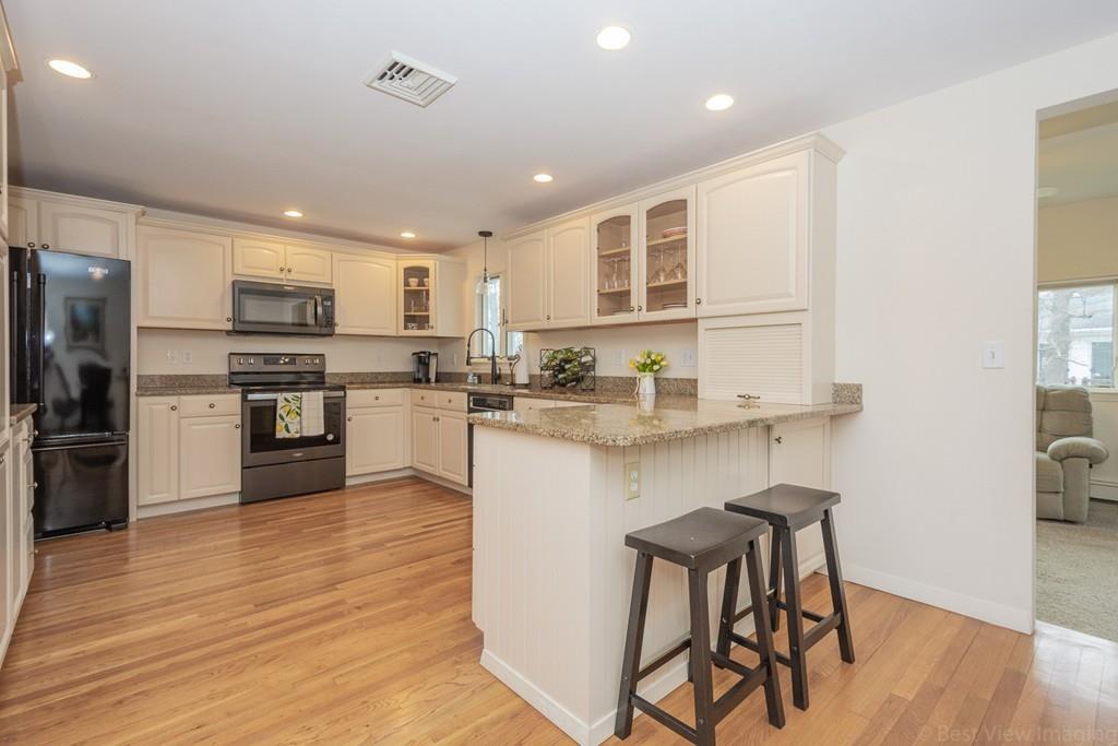 18 Harding Street Milford, MA 01757 - Photo 4 of 28 a kitchen with stainless steel appliances granite countertop a refrigerator a stove top oven a sink dishwasher and white cabinets with wooden floor