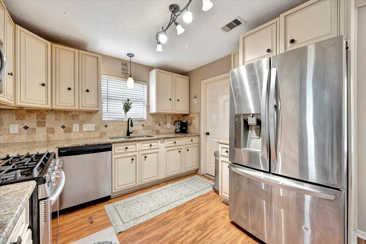 4235 Park Ridge Drive Pasadena, TX 77504 - Photo 19 of 41 a kitchen with stainless steel appliances granite countertop a refrigerator a sink dishwasher a stove and white cabinets with wooden floor