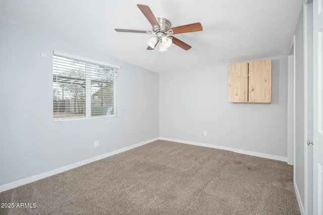 an empty room with a window and a ceiling fan