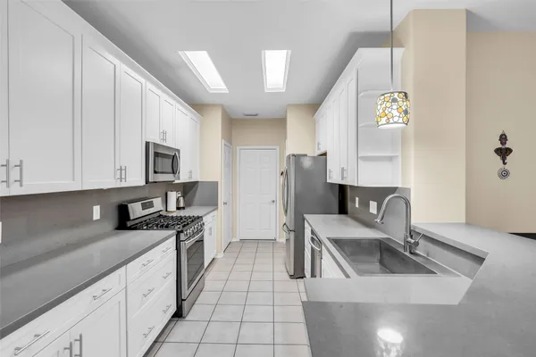 a kitchen with stainless steel appliances granite countertop a sink a stove top oven a chimney and a center island