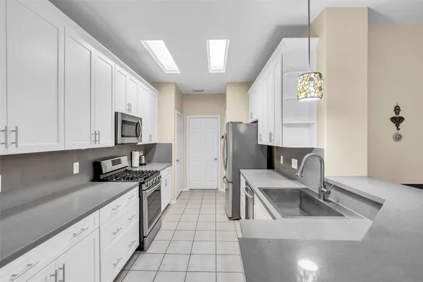 a kitchen with stainless steel appliances granite countertop a sink a stove top oven a chimney and a center island