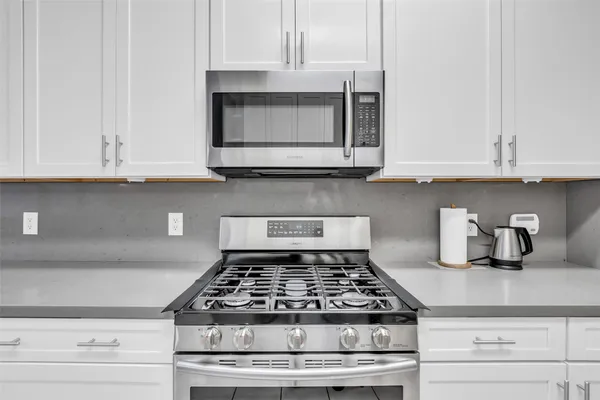 a kitchen with granite countertop white cabinets and stainless steel appliances