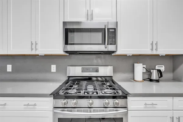 a kitchen with granite countertop white cabinets and stainless steel appliances