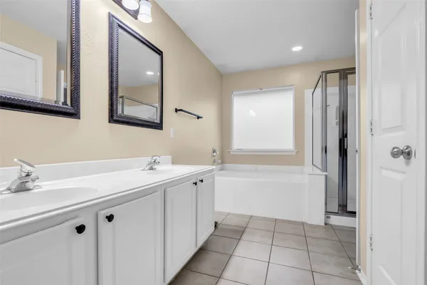 a bathroom with a double vanity sink mirror and bathtub