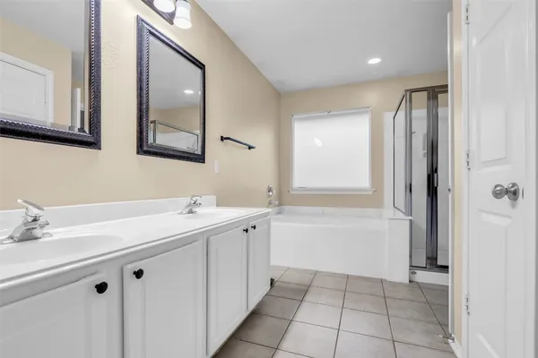 a bathroom with a double vanity sink mirror and bathtub