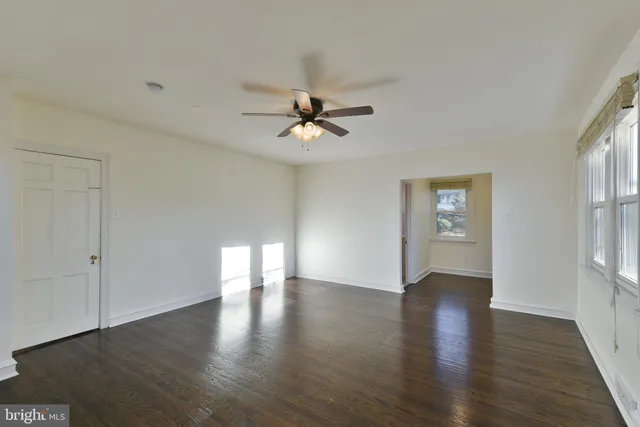 an empty room with wooden floor and a ceiling fan