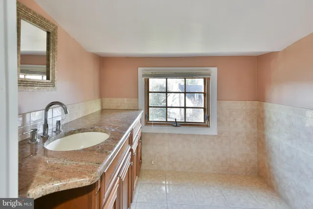 a bathroom with a granite countertop sink a mirror and a bathtub