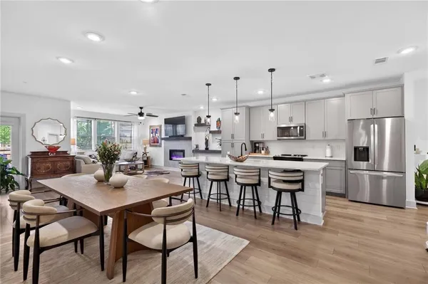 a kitchen with a dining table chairs wooden floor appliances and cabinets