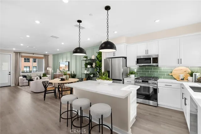 a kitchen with stainless steel appliances a sink a stove a refrigerator cabinets and chairs
