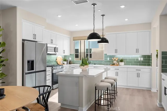 a kitchen with stainless steel appliances kitchen island granite countertop a sink a stove and refrigerator