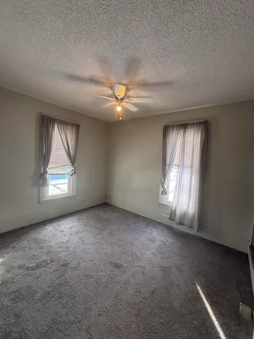 an empty room with windows and fan