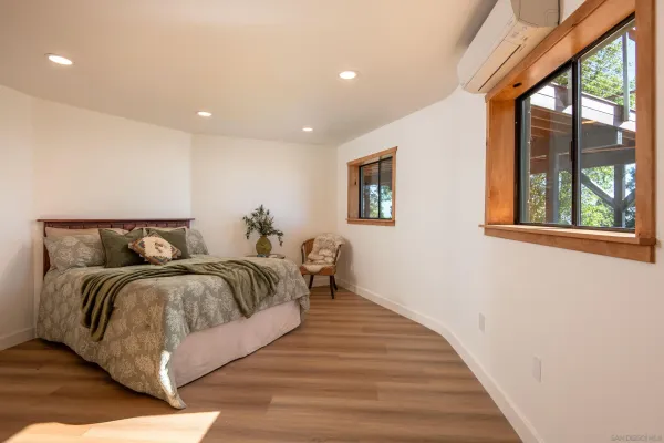 a spacious bedroom with a bed and wooden floor