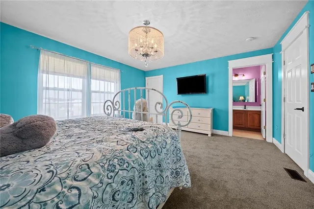 a bedroom with a bed and a flat tv screen on dresser