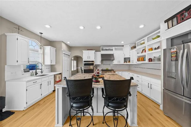 a kitchen with stainless steel appliances a dining table chairs refrigerator and sink