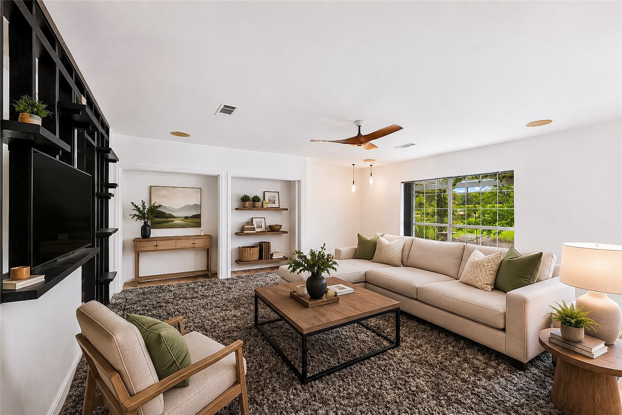 358 Easley Road Smithville, TX 78957 - Photo 20 of 36 Virtually staged - Living area with warm lighting, built-in shelving, and a large window overlooking lush greenery.