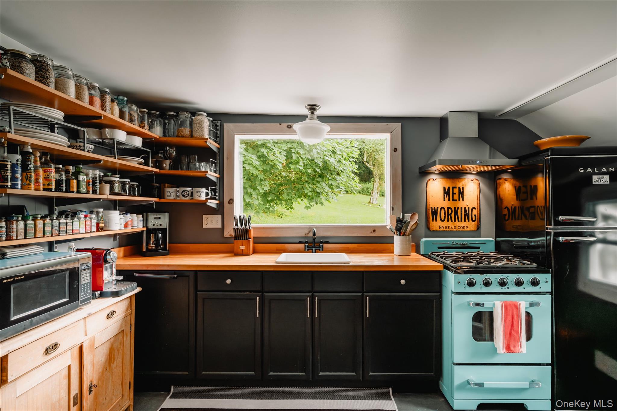 1680 Gulf Road North Branch, NY 12766 - Photo 28 of 45 Studio kitchen with gas range gas stove, wall chimney range hood, stainless steel microwave, refrigerator, and open shelves