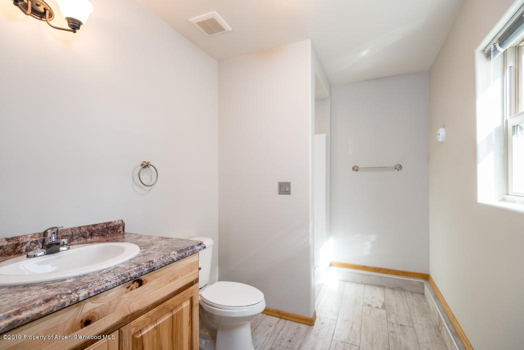 1317 East 17th Street Rifle, CO 81650 - Photo 37 of 57 a bathroom with a granite countertop sink a toilet and a mirror