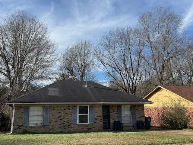 a front view of house with yard and trees in the background