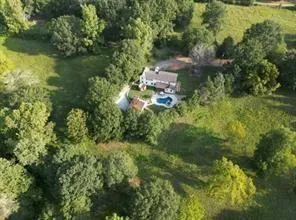 an aerial view of residential house with outdoor space and trees all around