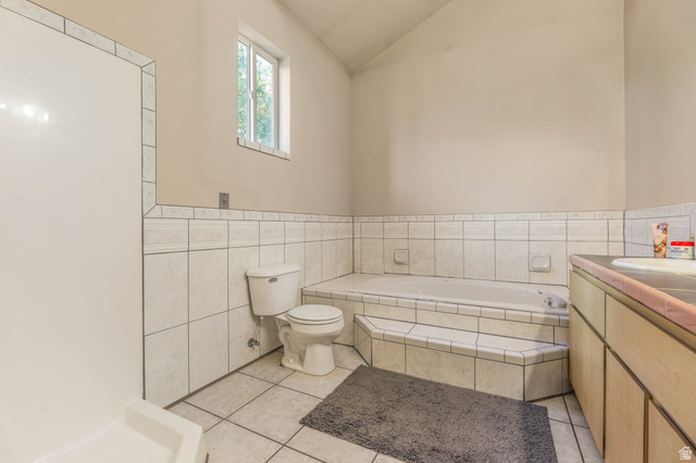 569 Elk Meadow Loop Tooele, UT 84074 - Photo 39 of 56 Full bath featuring vanity, a garden tub, light tile patterned floors, lofted ceiling, and tile walls