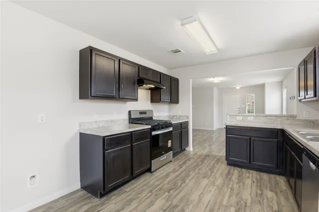 a kitchen with stainless steel appliances granite countertop wooden cabinets a stove top oven a sink and dishwasher