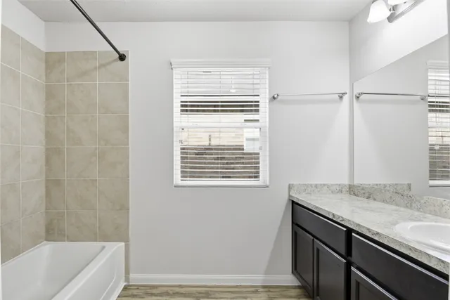 a bath room with a granite countertop sink and a bathtub
