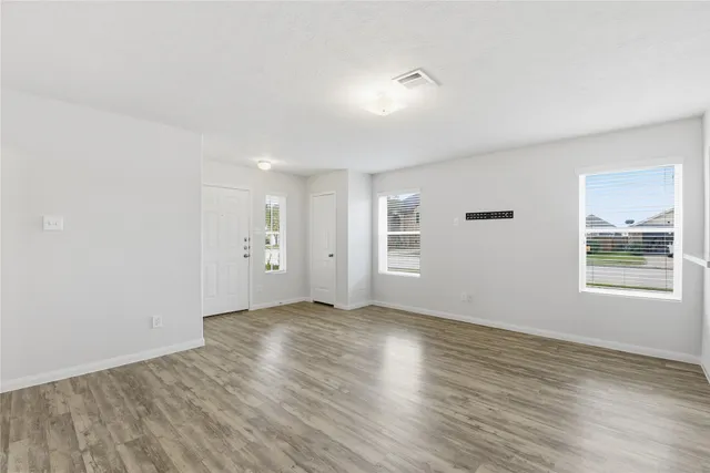 an empty room with wooden floor and windows
