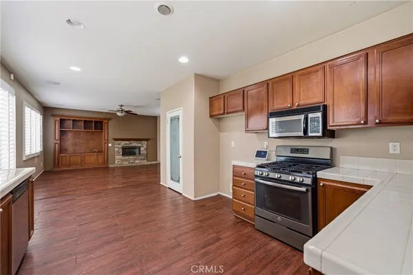 a large kitchen with a large counter top a sink stainless steel appliances and cabinets