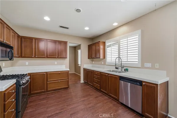 an empty room with wooden floor a ceiling fan and windows