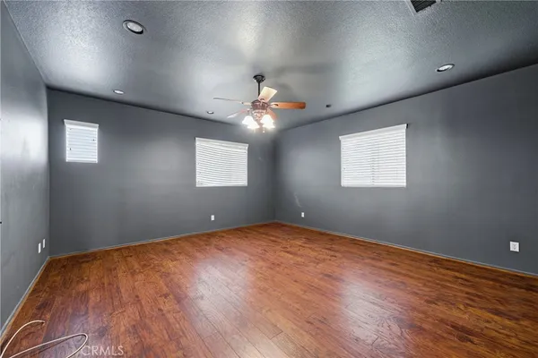 an empty room with wooden floor chandelier and windows