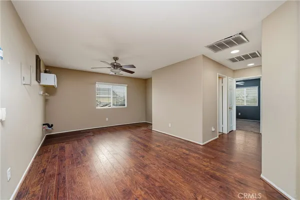 a view of empty room with wooden floor and fan