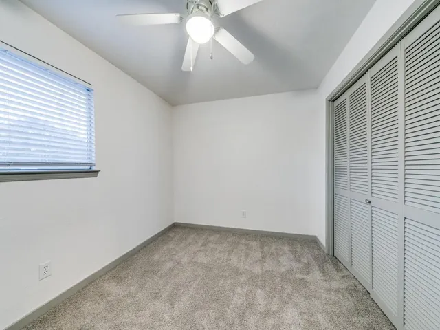 an empty room with a chandelier fan and windows