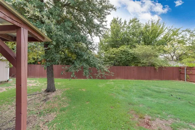 a view of a backyard with large trees and a barn in the background