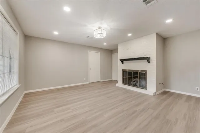 an empty room with wooden floor fireplace and windows