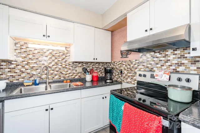 a kitchen with stainless steel appliances a stove and white cabinets