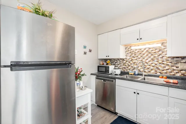 a kitchen with stainless steel appliances a refrigerator and white cabinets