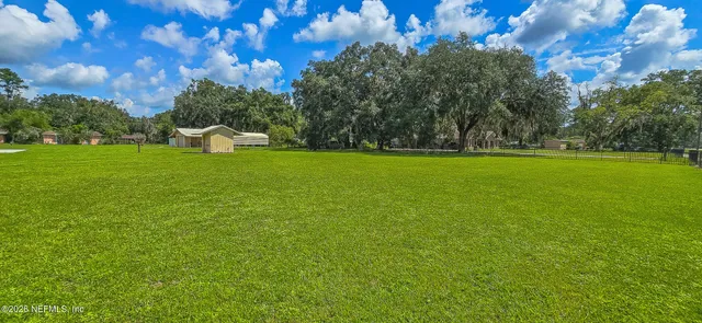 a view of a green field with wooden fence