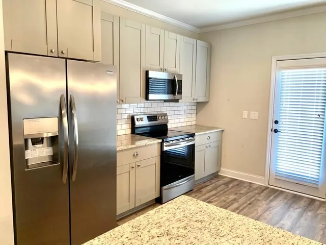 a kitchen with stainless steel appliances granite countertop a refrigerator a stove and a sink with wooden floor