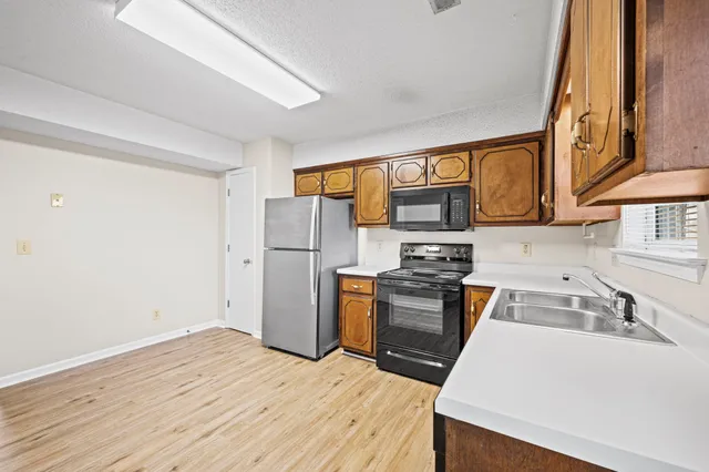a kitchen with granite countertop a refrigerator stove top oven and sink