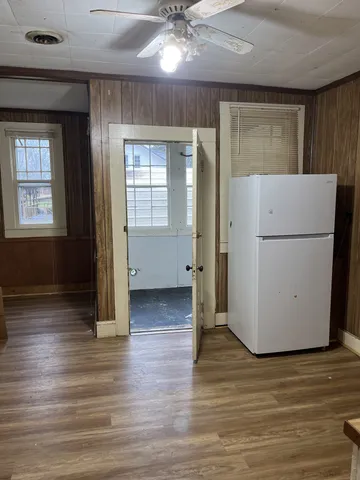 a view of a livingroom with wooden floor and a kitchen space