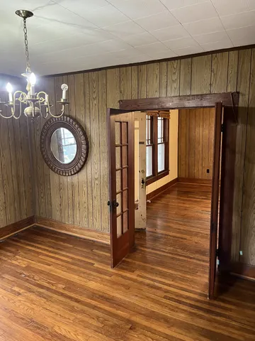 a view of a hallway with wooden floor and a kitchen space