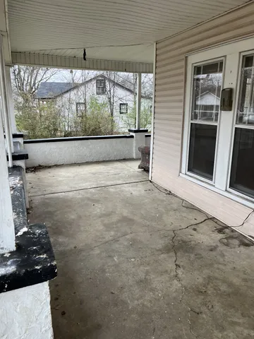 a view of a porch with a floor to ceiling window and wooden floor