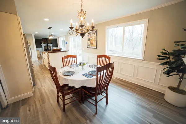 a kitchen with stainless steel appliances kitchen island granite countertop a refrigerator a stove a sink a dining table and chairs with wooden floor