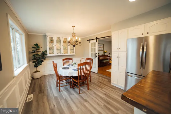 a kitchen with stainless steel appliances kitchen island granite countertop a stove a sink a refrigerator and white cabinets with wooden floor