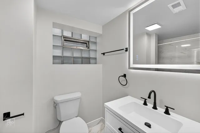 a bathroom with a toilet a sink and mirror