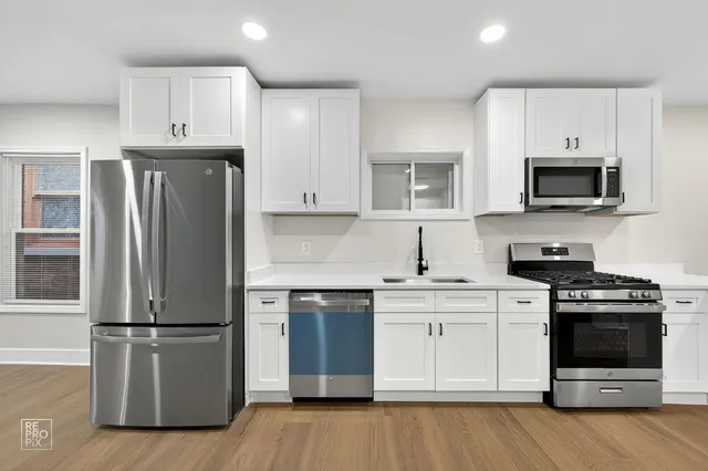 a kitchen with cabinets stainless steel appliances and wooden floor