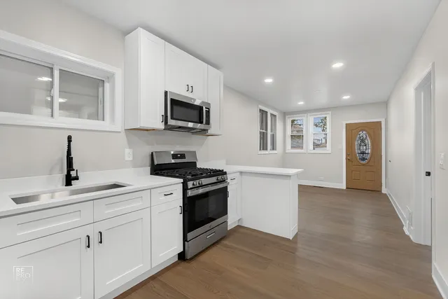 a kitchen with stainless steel appliances granite countertop a sink dishwasher a stove and a refrigerator with wooden floor