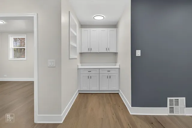 a view of a kitchen with white cabinets and wooden floor
