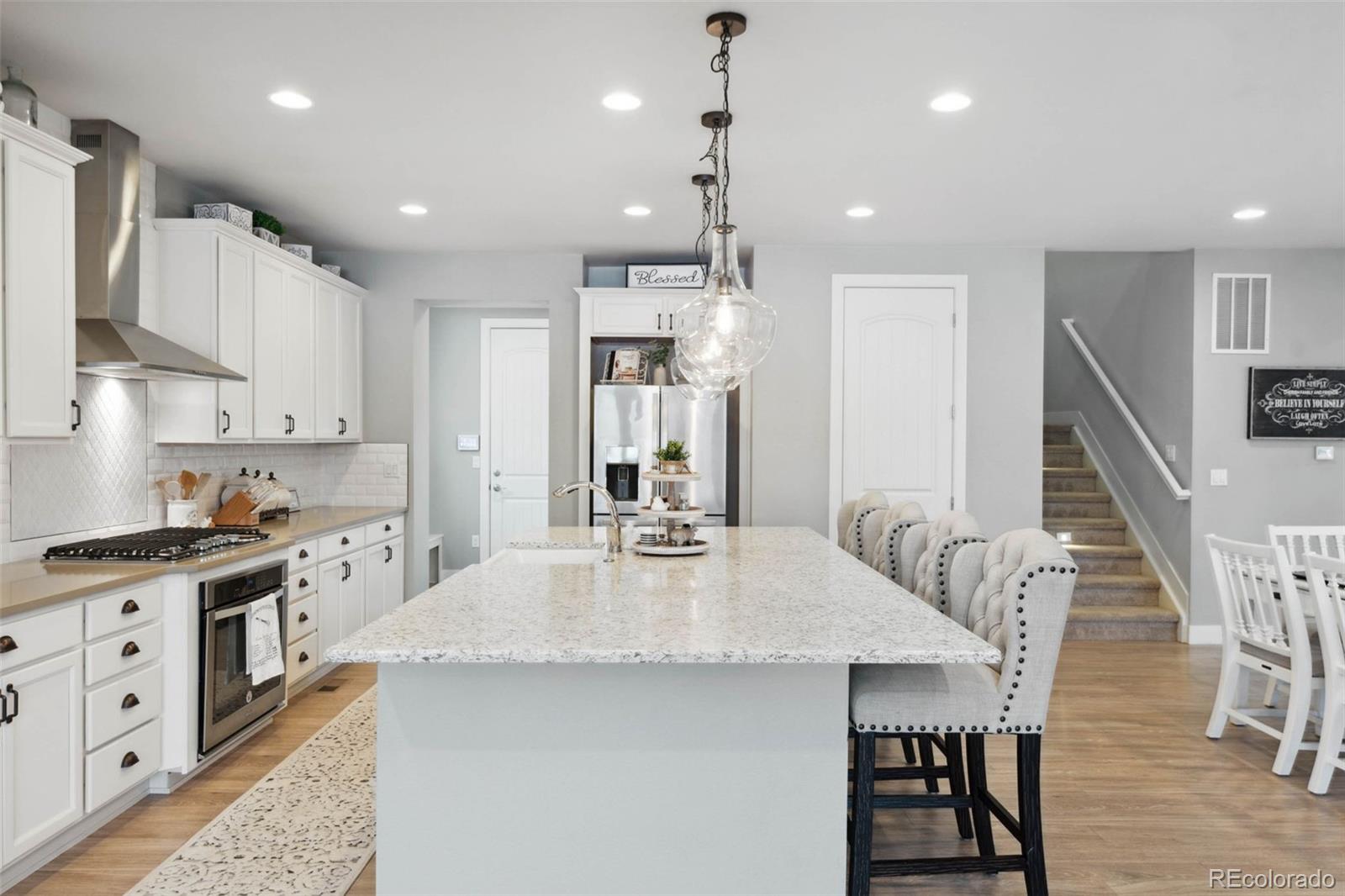 9459 Gore Loop Arvada, CO 80007 - Photo 13 of 50 a kitchen with stainless steel appliances kitchen island granite countertop a dining table chairs sink and cabinets