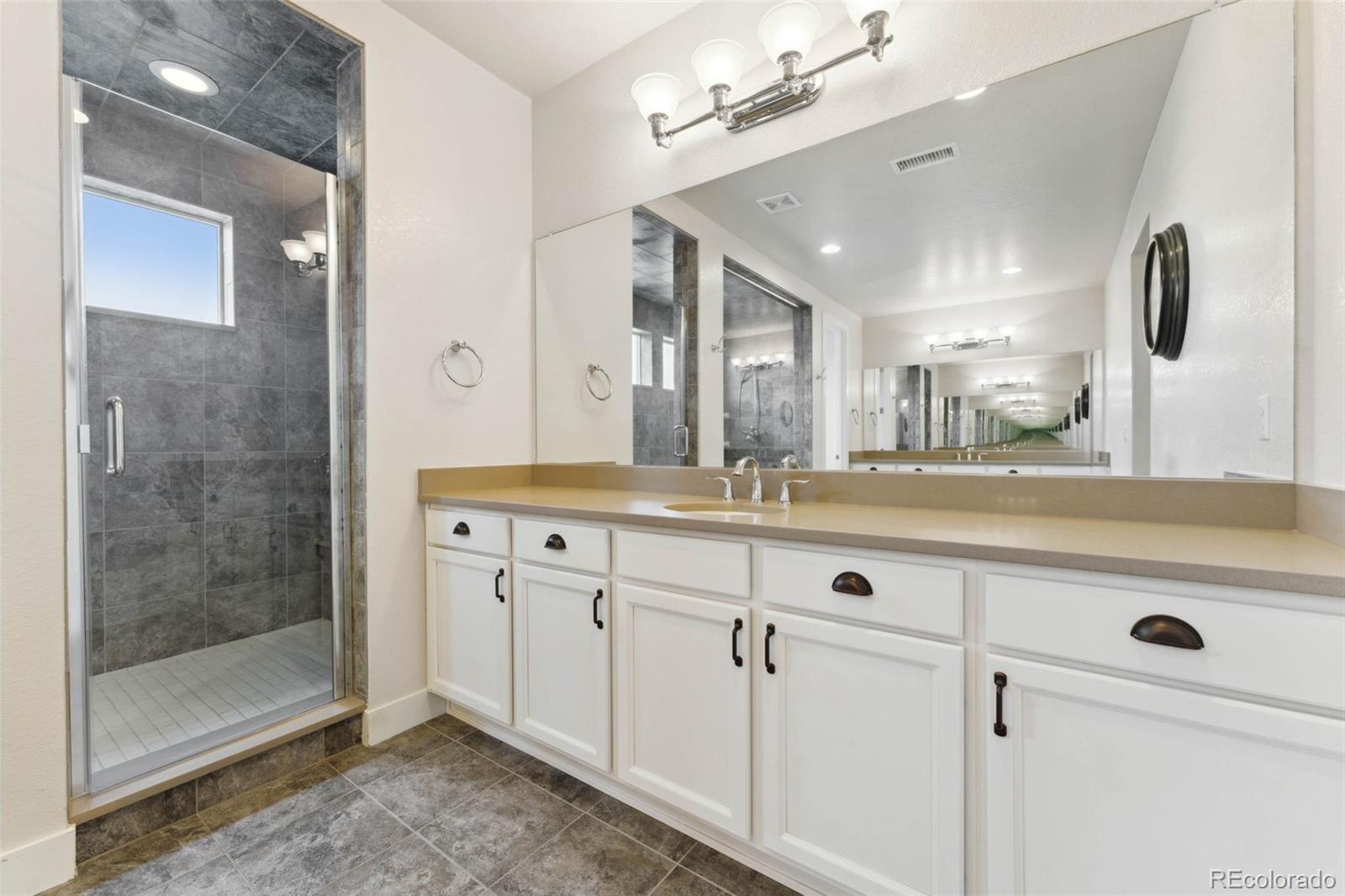 9459 Gore Loop Arvada, CO 80007 - Photo 28 of 50 a spacious bathroom with a shower a sink and mirror